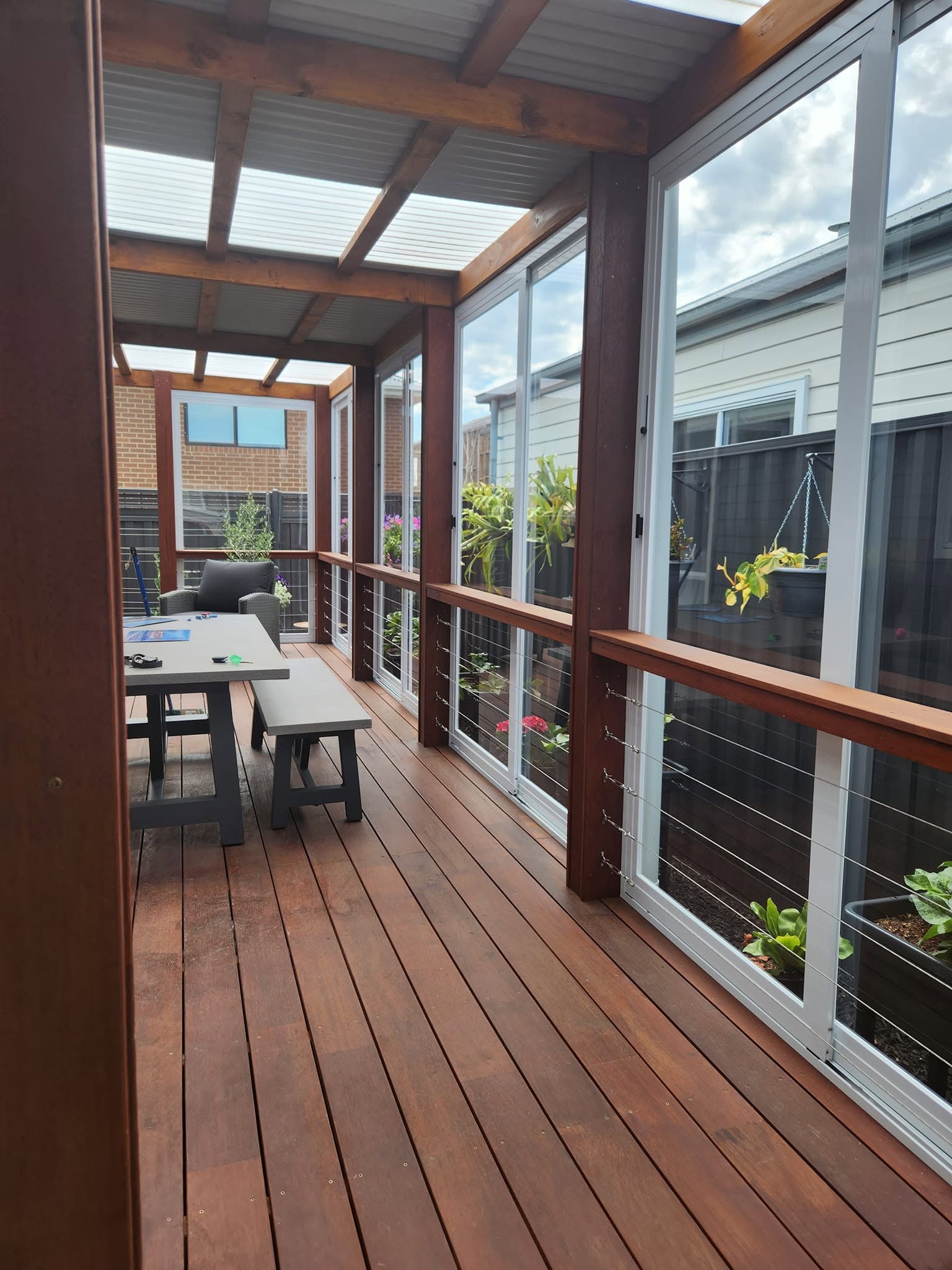White framed weather screens enclosing a timber entertaining deck