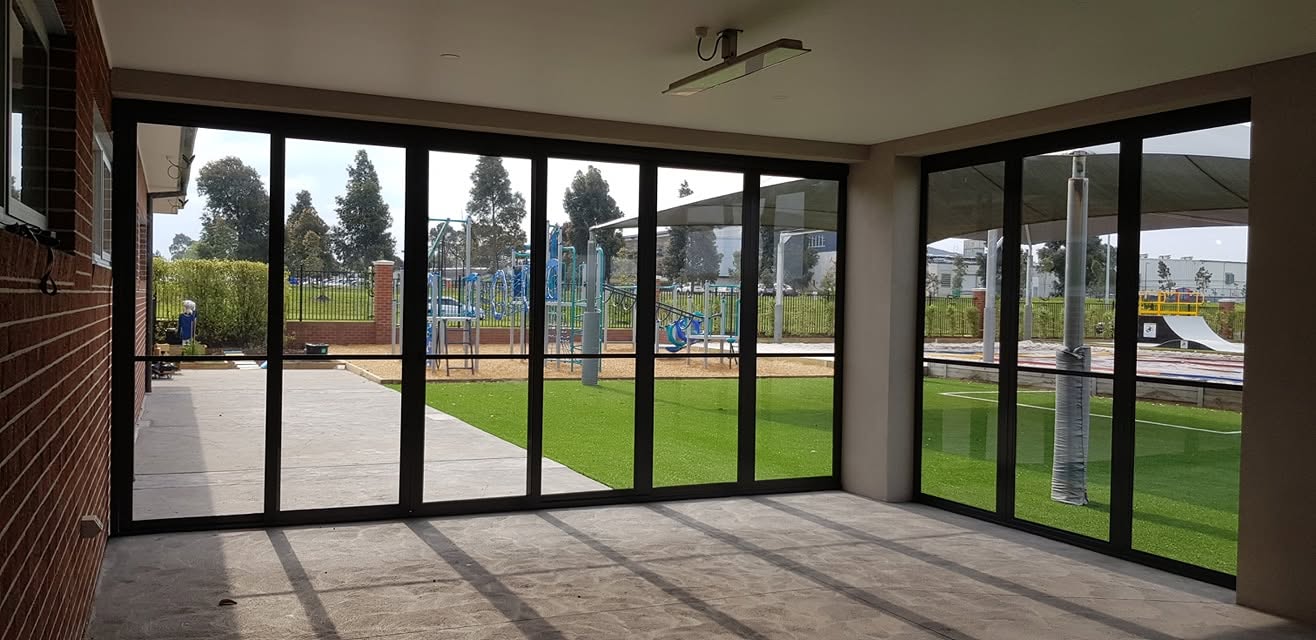 Black framed clear weather screens enclosing a spacious communal alfresco area