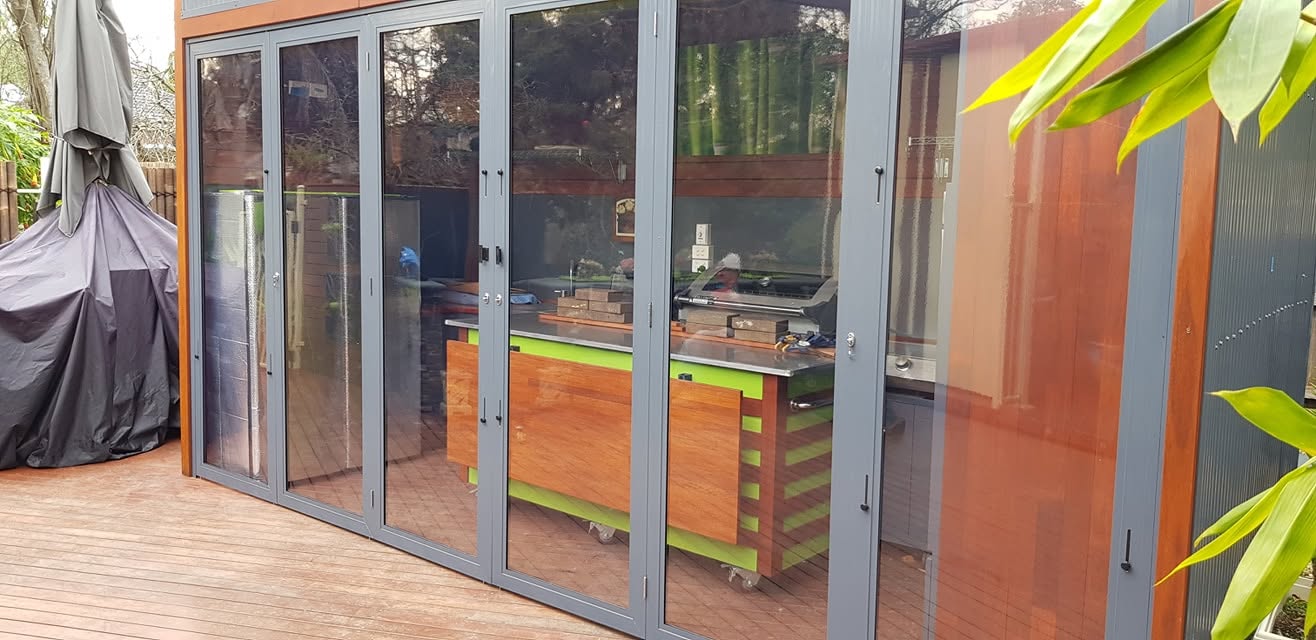 Charcoal framed weather screens enclosing an outdoor kitchen and deck