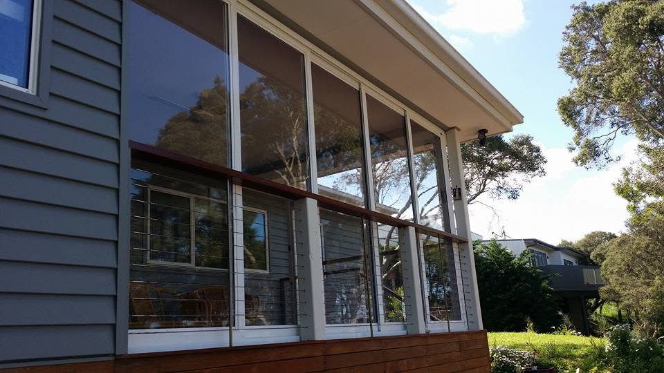 White framed clear weather screens enclosing an elevated timber veranda