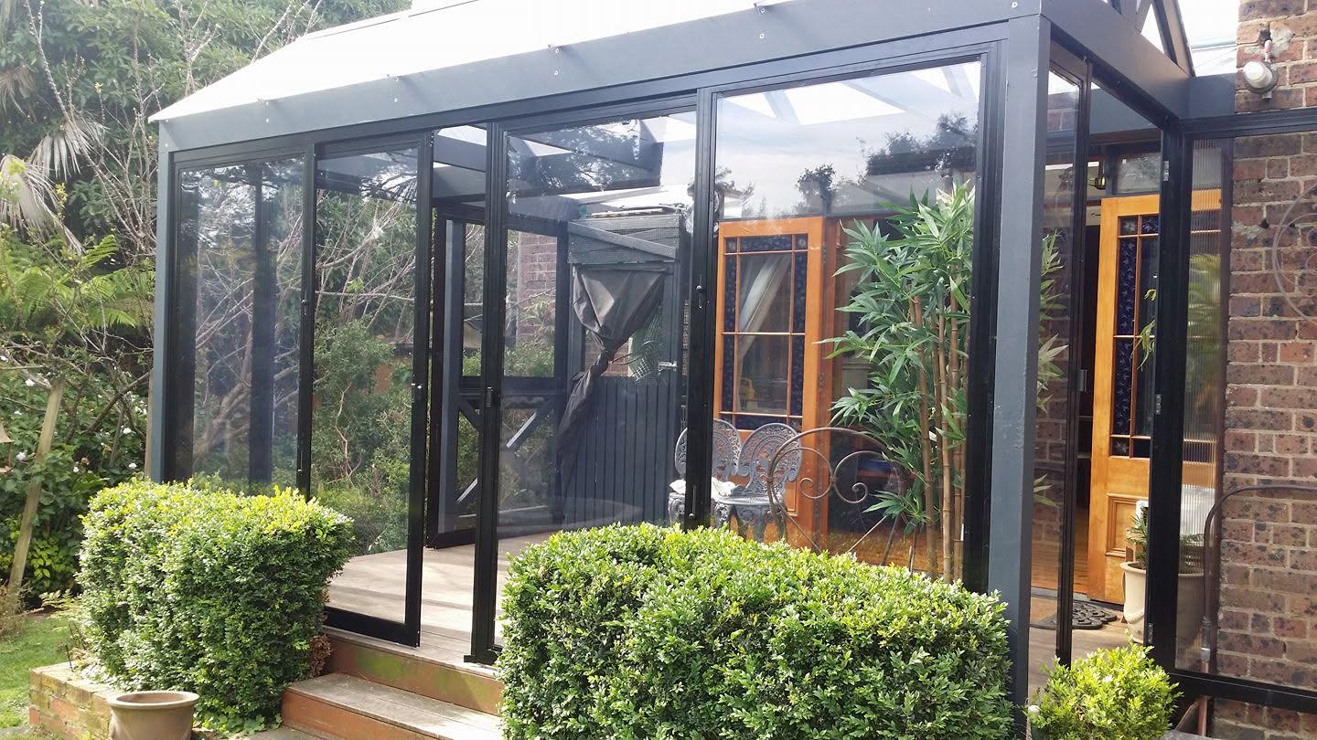 Black framed clear weather screens enclosing a garden sunroom