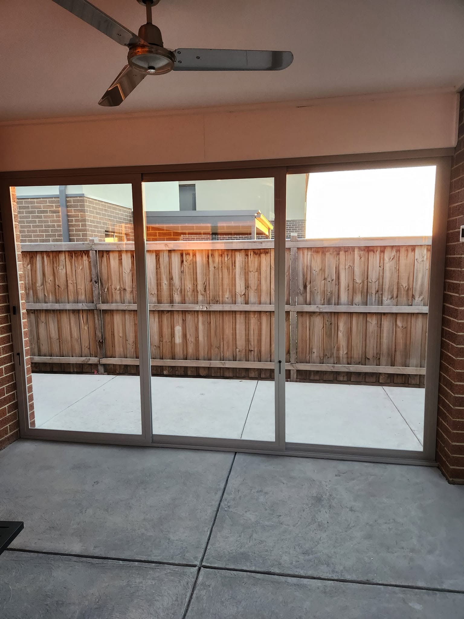 Grey framed weather screens enclosing a brick alfresco area
