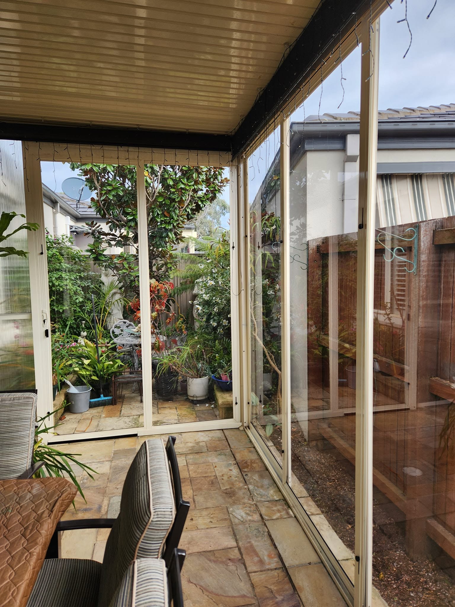 Cream framed weather screens surrounding a garden dining area