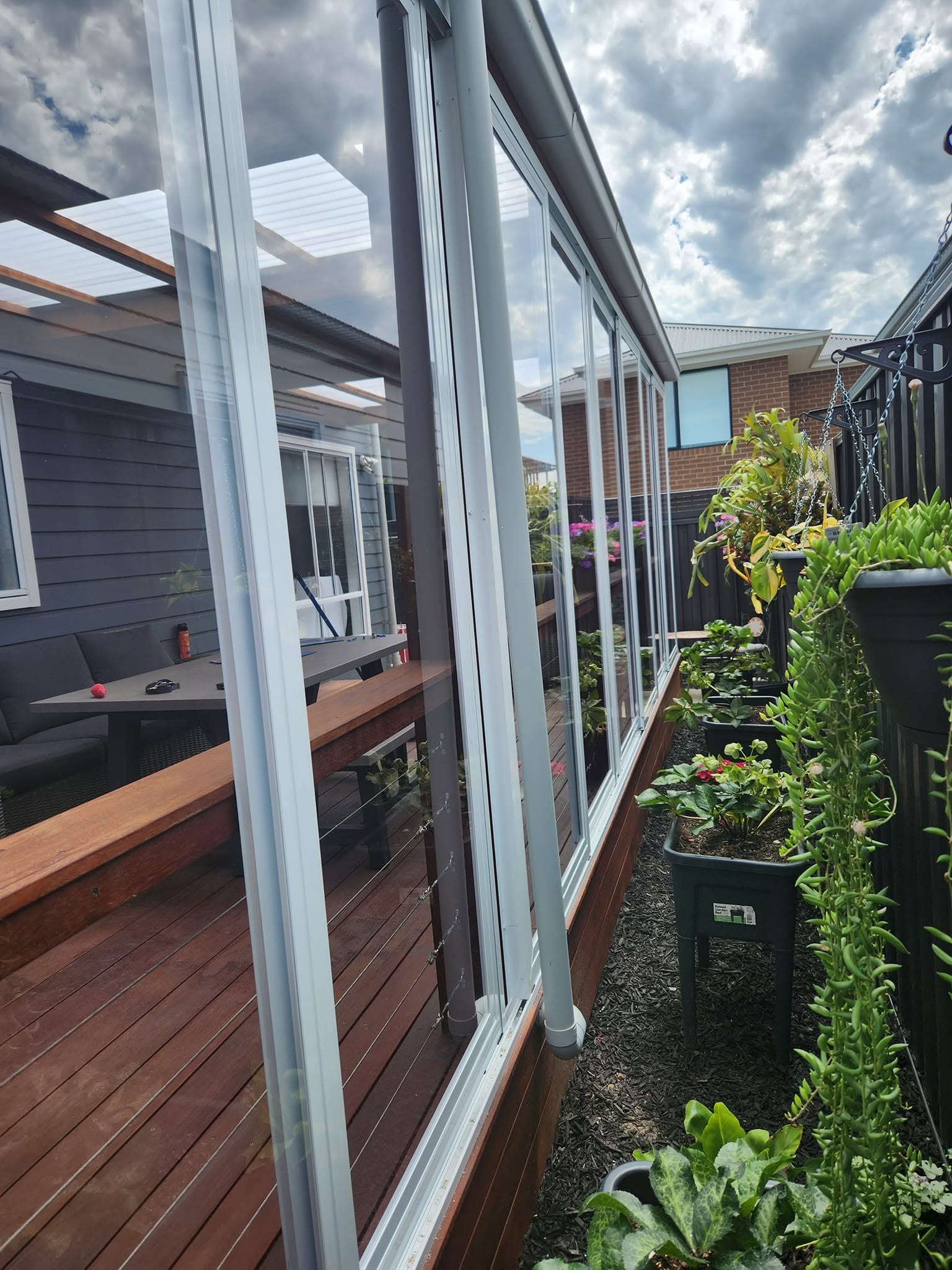 White framed weather screens fitted along a narrow garden deck